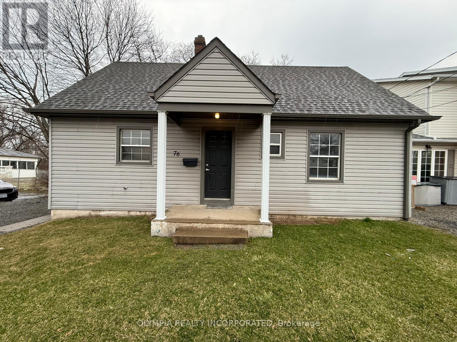 A small house with a front porch and a black door.