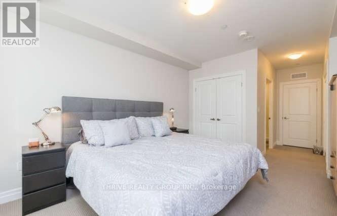 A bedroom with a large bed and a nightstand with a lamp.