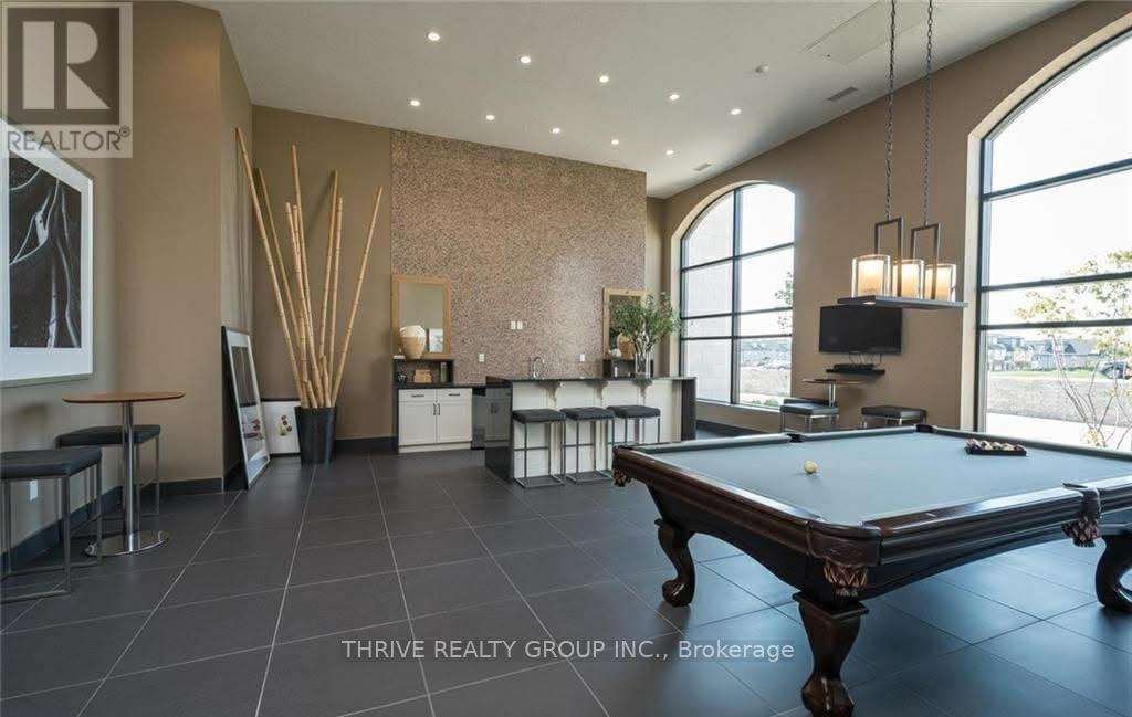 A pool table is in the middle of a room with a tv and a plant.
