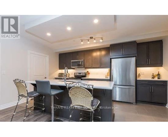 A kitchen with a table and chairs in front of a refrigerator.