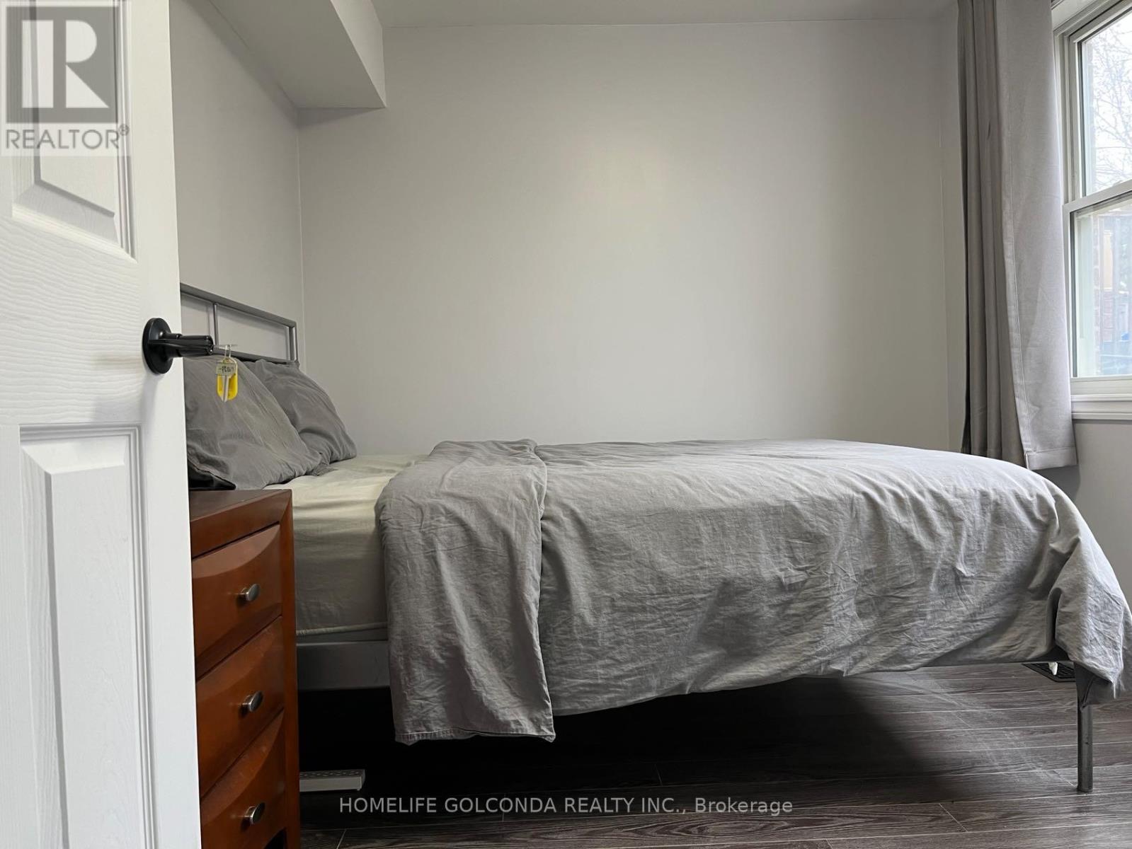 A bedroom with a bed, nightstand, and window.