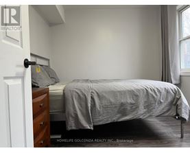 A bedroom with a bed, nightstand, and window.