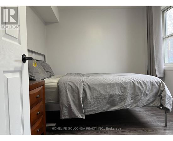 A bedroom with a bed, nightstand, and window.