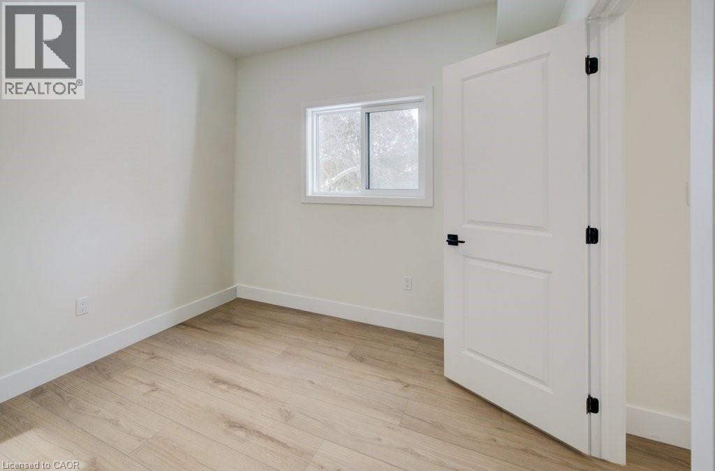 A room with a white door and a window with a view of trees outside.