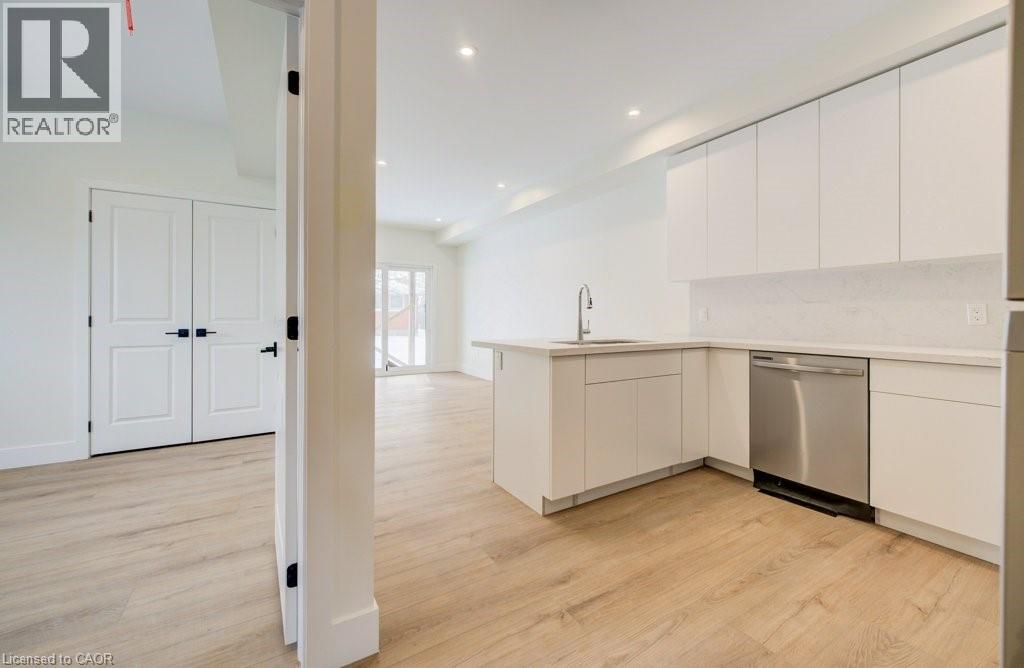A modern kitchen with white cabinets and a wooden floor.