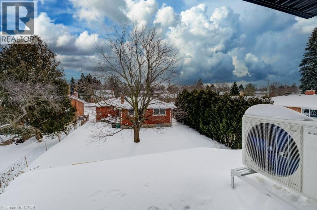 A snow-covered landscape with a house and trees in the background.