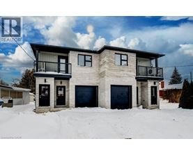 A two-story house with a balcony on the second floor is surrounded by snow.