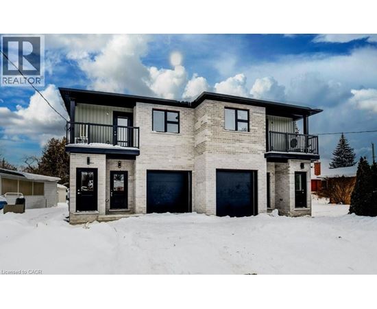 A two-story house with a balcony on the second floor is surrounded by snow.