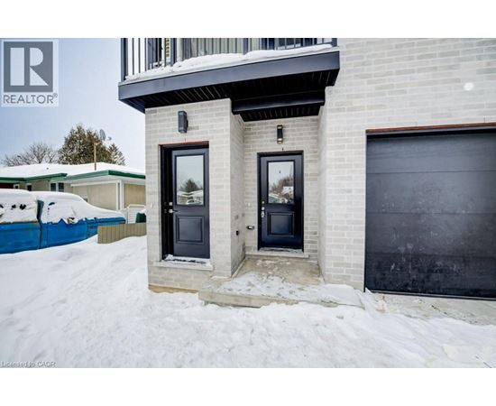 A house with a black door and a window is surrounded by snow.