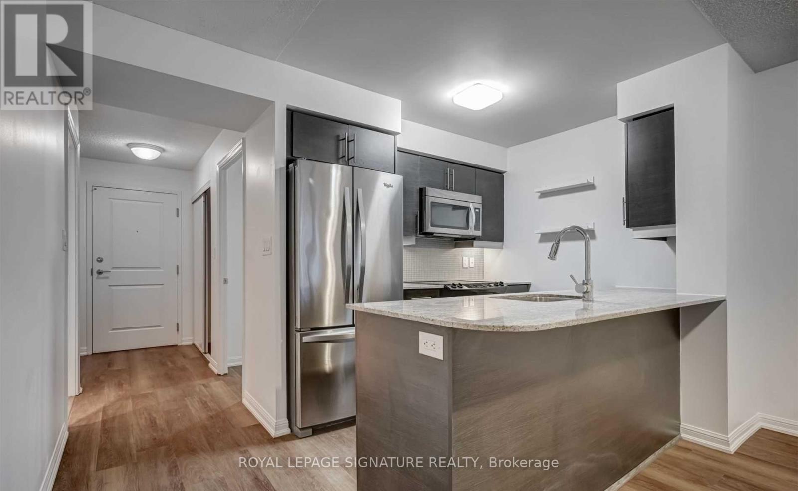 A modern kitchen with stainless steel appliances and a wooden floor.