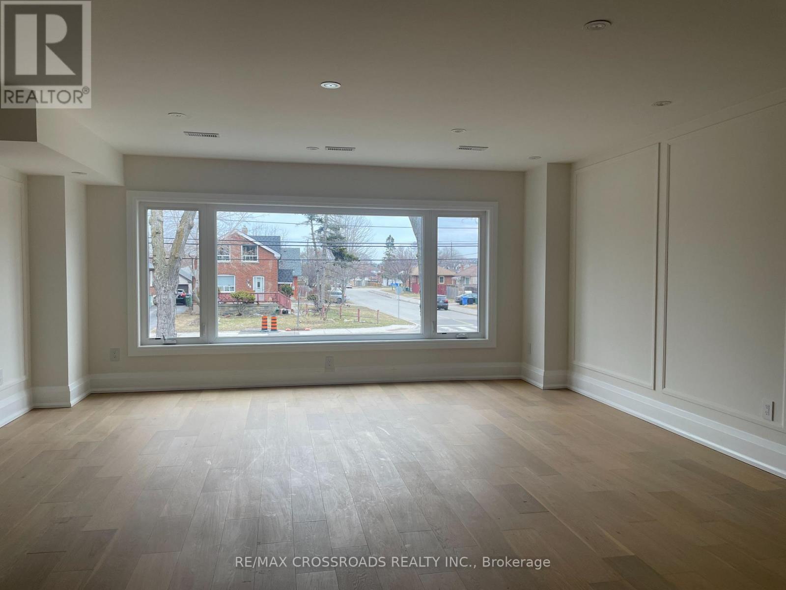 A room with a large window and wooden flooring.