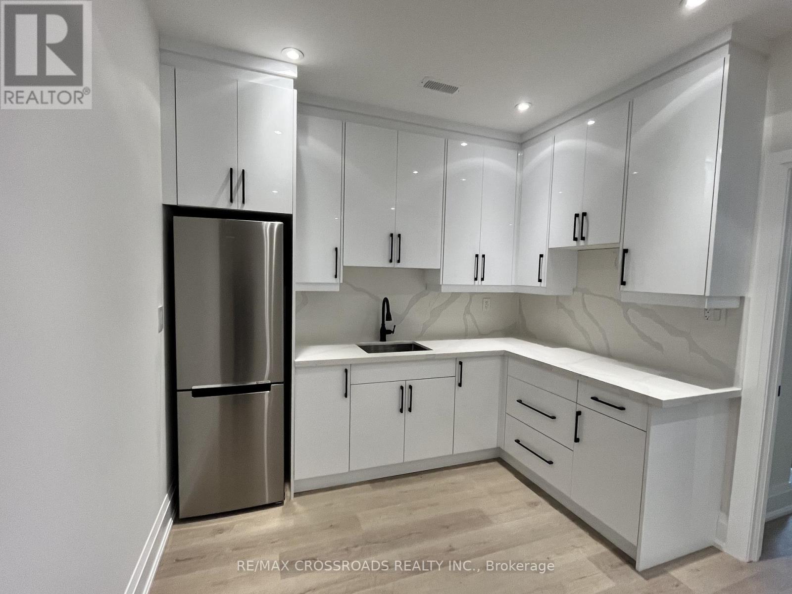 A kitchen with white cabinets and a stainless steel refrigerator.