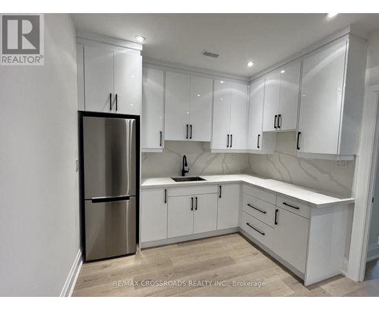 A kitchen with white cabinets and a stainless steel refrigerator.