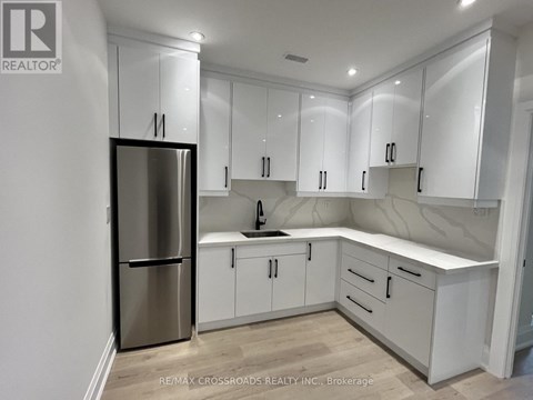 A kitchen with white cabinets and a stainless steel refrigerator.