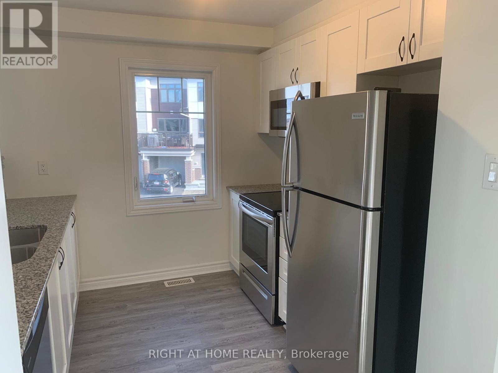 A kitchen with a refrigerator, sink, and oven.