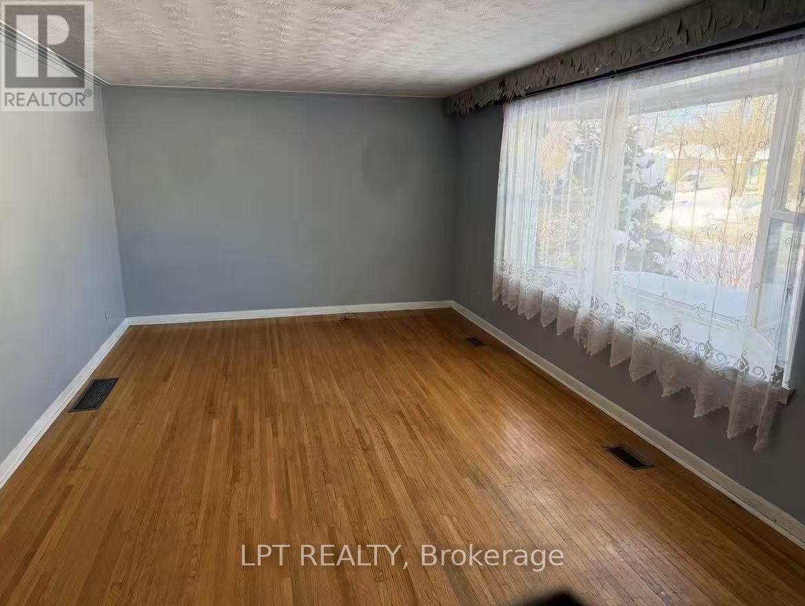 A room with wooden flooring and a window with curtains.