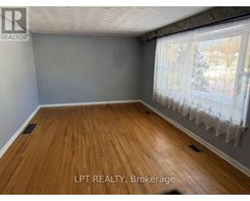 A room with wooden flooring and a window with curtains.
