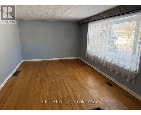 A room with wooden flooring and a window with curtains.