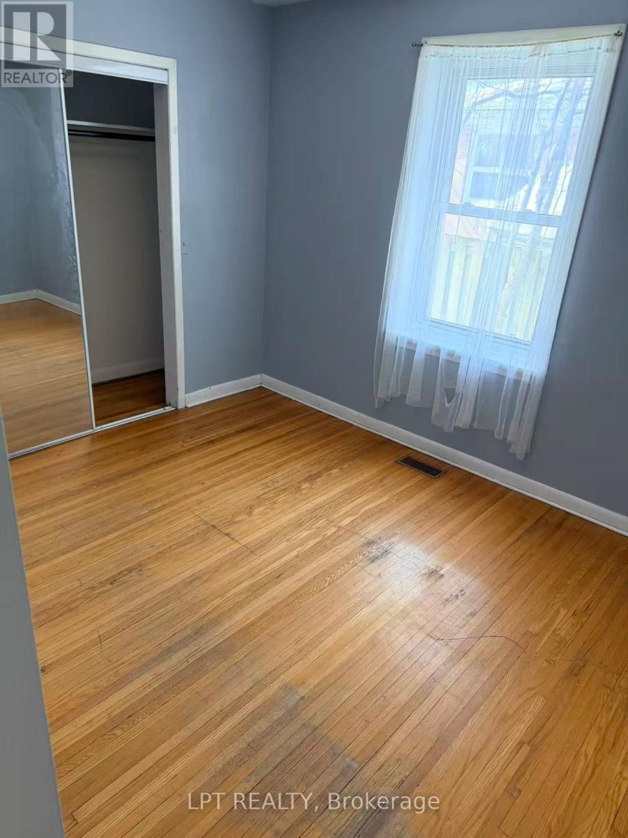 A room with wooden flooring and a window with curtains.