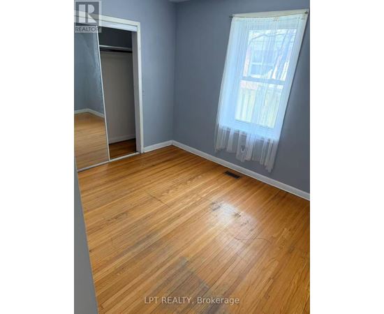 A room with wooden flooring and a window with curtains.