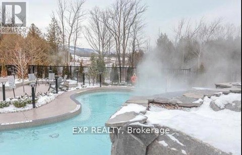 A hot tub in a snowy landscape with steam rising from it.