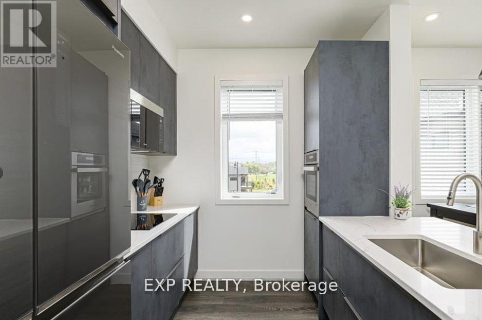 A modern kitchen with dark grey cabinets and a large window.
