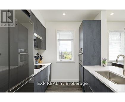 A modern kitchen with dark grey cabinets and a large window.