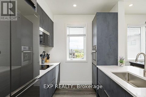 A modern kitchen with dark grey cabinets and a large window.