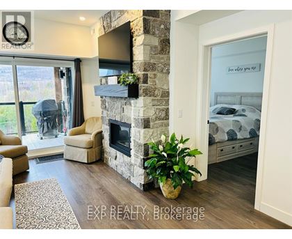 A living room with a stone fireplace and a television mounted above it.