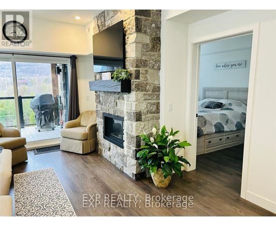 A living room with a stone fireplace and a television mounted above it.