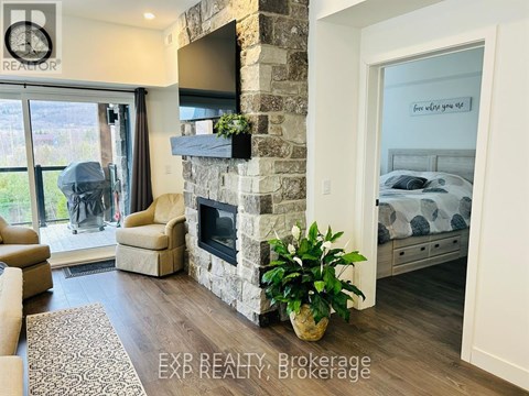 A living room with a stone fireplace and a television mounted above it.