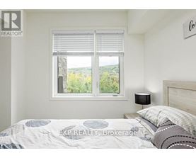 A bedroom with a bed, a window with blinds, and a lamp on the nightstand.