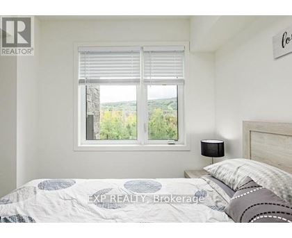 A bedroom with a bed, a window with blinds, and a lamp on the nightstand.