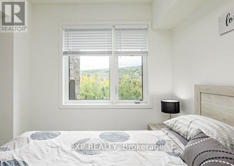 A bedroom with a bed, a window with blinds, and a lamp on the nightstand.