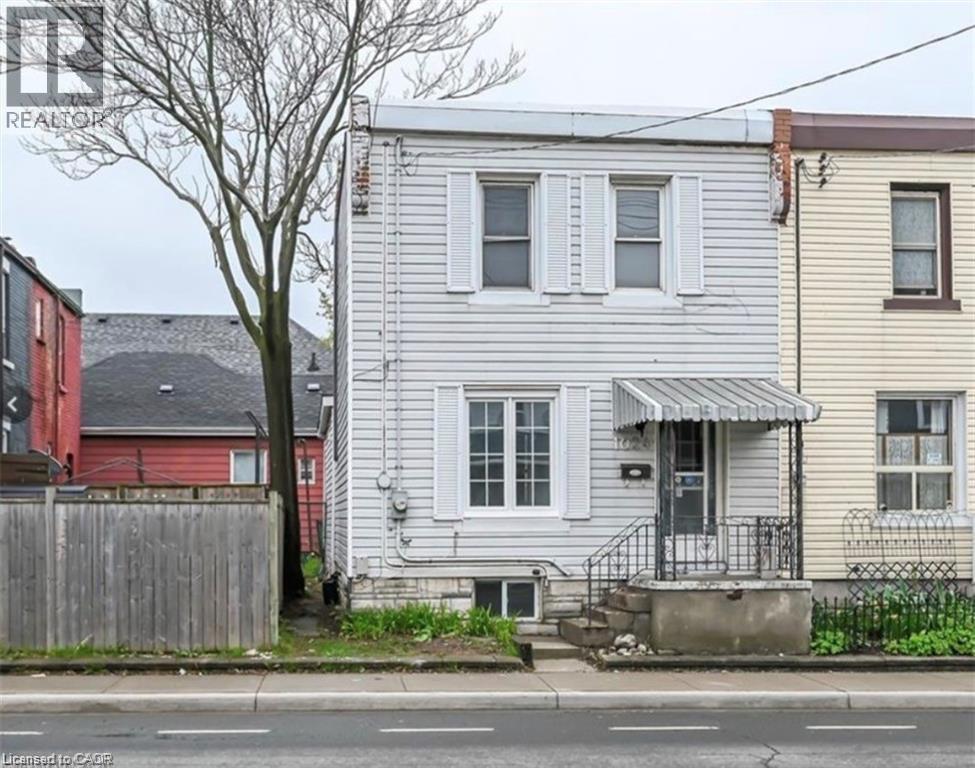 A white house with a grey roof is in front of a red house.
