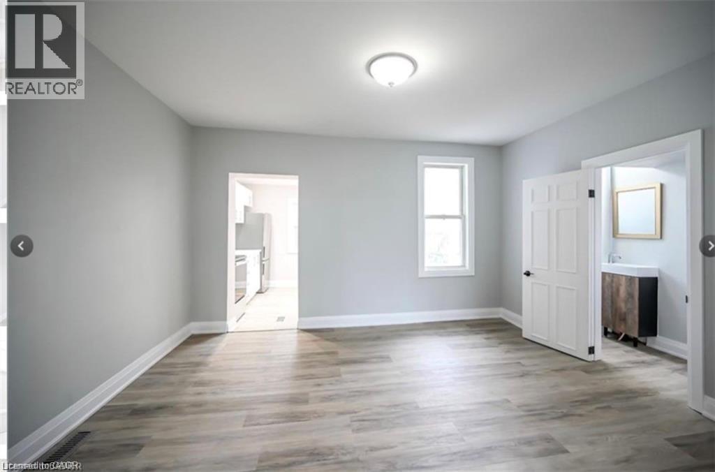 A spacious room with wooden flooring and white walls.