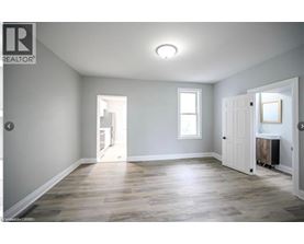 A spacious room with wooden flooring and white walls.