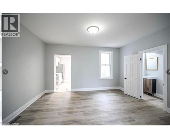 A spacious room with wooden flooring and white walls.