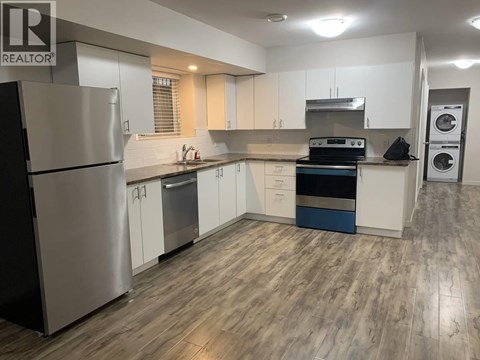 A modern kitchen with a stainless steel refrigerator and wooden flooring.