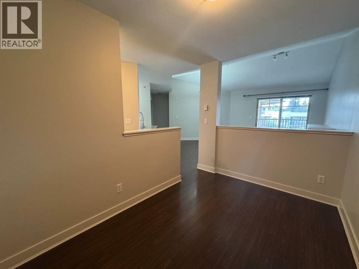 A spacious room with wooden floors and white walls, with a window on the right side.
