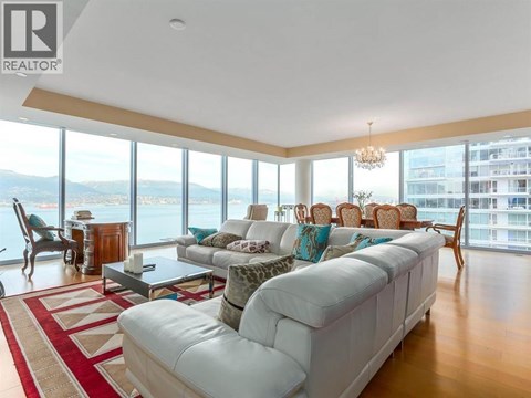 A living room with a white couch and a large window overlooking a body of water.