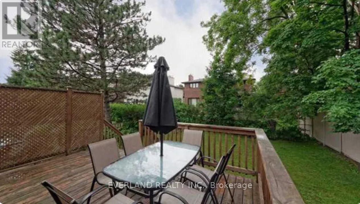 A patio with a glass table and chairs and a black umbrella.