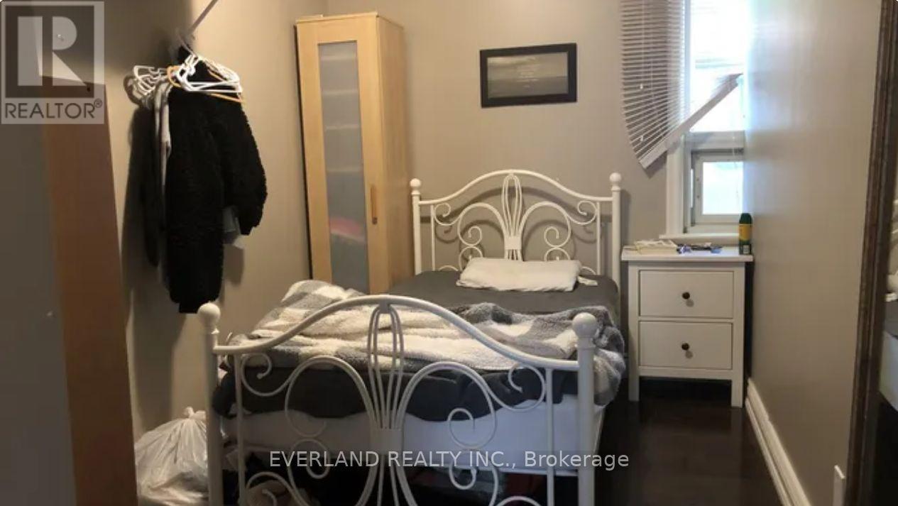 A bedroom with a white bed and a wooden dresser.