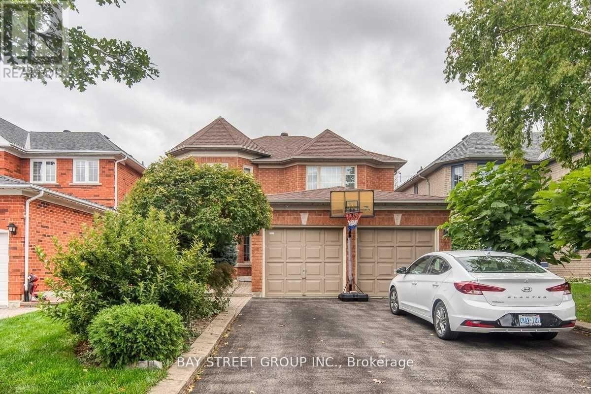 A white car is parked in front of a house with a garage.