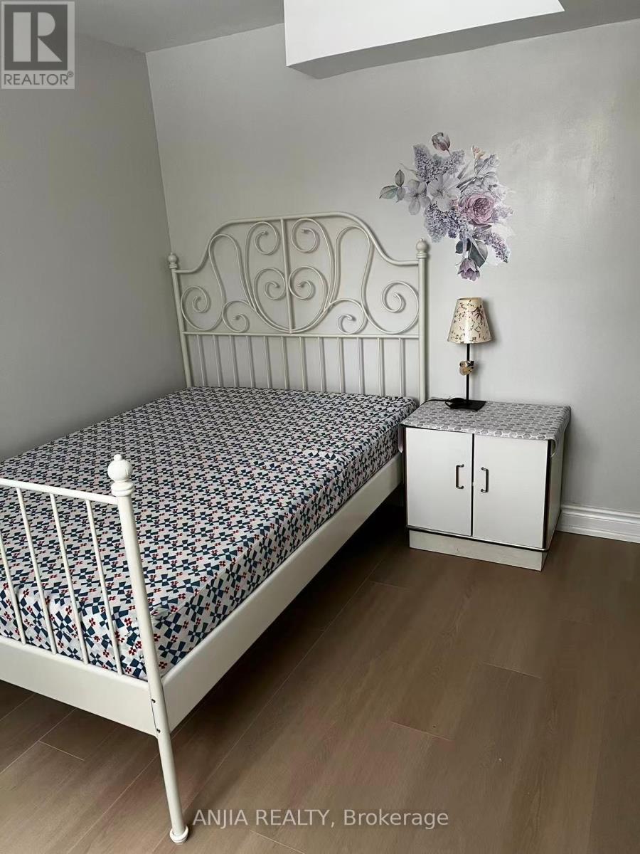 A bedroom with a white metal bed frame and a floral patterned bedspread.