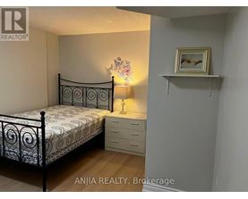 A bedroom with a white metal bed frame and a floral patterned bedspread.