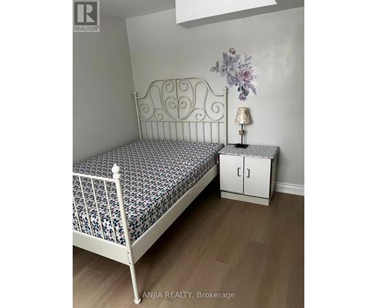 A bedroom with a white metal bed frame and a floral patterned bedspread.