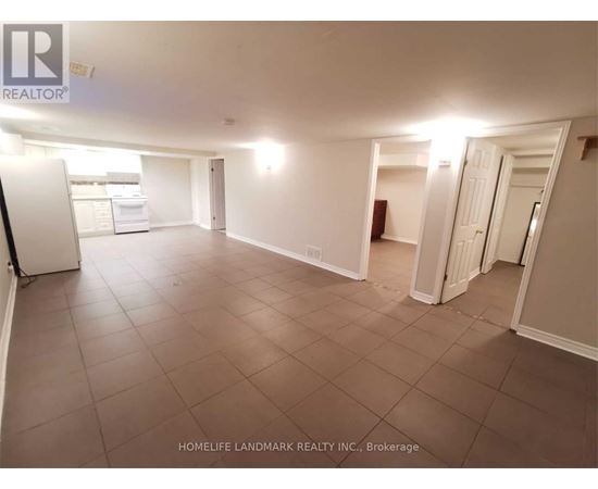 A spacious room with tile flooring and white walls, with a refrigerator on the left side.