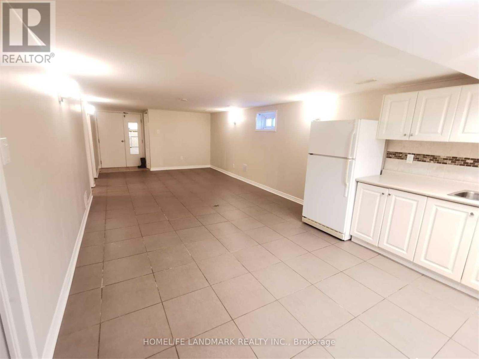 A spacious room with a kitchenette and tiled flooring.