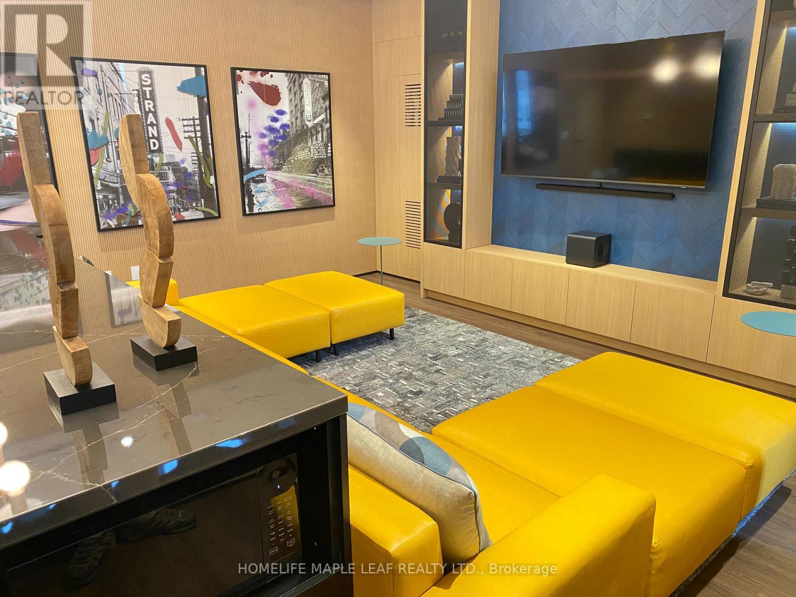 A living room with a yellow couch and a flat screen TV mounted on the wall.